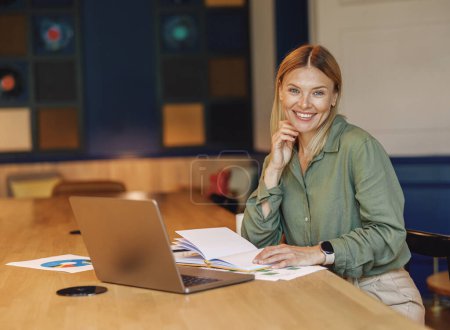 Foto de Mujer gerente de ventas sentado en coworking moderno y trabajando en el ordenador portátil. Foto de alta calidad - Imagen libre de derechos