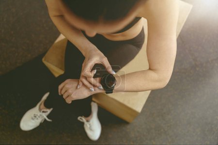 Photo for Top view of woman looking at smartwatch on her wrist while resting after workout. High quality photo - Royalty Free Image
