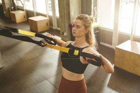 Photo for Young fit woman training in trx elastic rope at fitness gym center. High quality photo - Royalty Free Image