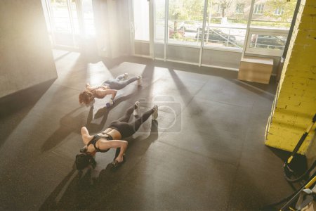 Foto de Dos mujeres haciendo ejercicio de flexiones con mancuerna. Mujeres fuertes haciendo ejercicio. Foto de alta calidad - Imagen libre de derechos