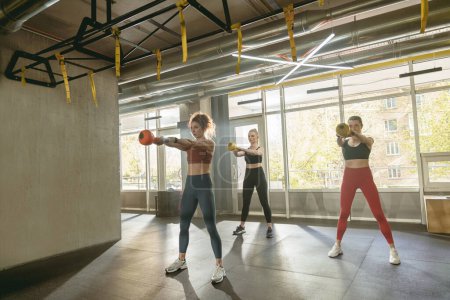 Téléchargez les photos : Groupe de femmes sportives faisant squats avec des poids dans leurs mains dans le club de sport. Photo de haute qualité - en image libre de droit
