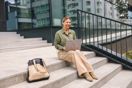 Photo for Business woman working on a laptop on stairs outdoors. Freelancer work online - Royalty Free Image