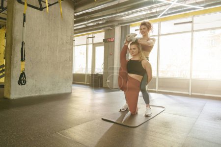 Foto de Mujer en forma haciendo ejercicios de estiramiento con la ayuda de entrenador personal en el gimnasio. Foto de alta calidad - Imagen libre de derechos