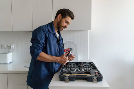Foto de Trabajador masculino con caja de herramientas de pie en el fondo de la cocina. Foto de alta calidad - Imagen libre de derechos
