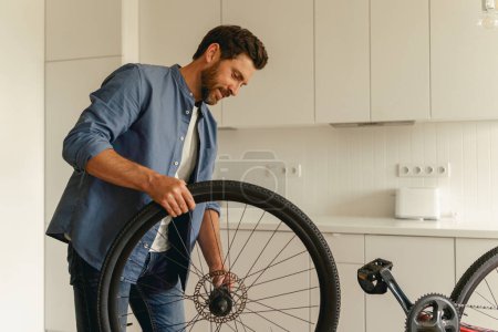 Photo for Handsome man in casual clothing repairing bicycle itself at home. High quality photo - Royalty Free Image