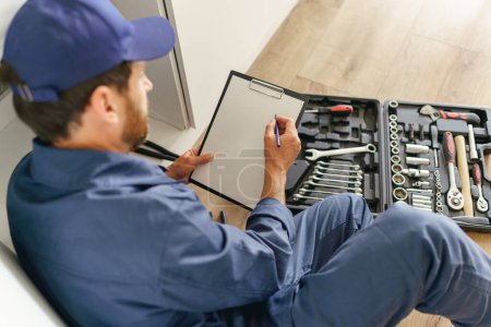 Photo for Close up of male worker with open toolbox sitting on home kitchen floor. High quality photo - Royalty Free Image