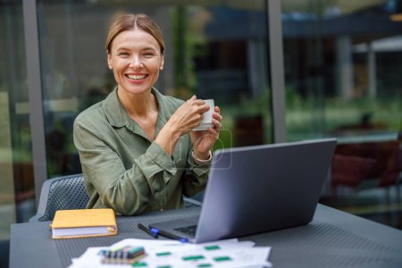Foto de Mujer de negocios sonriente trabajando en el ordenador portátil en la terraza de la cafetería. Foto de alta calidad - Imagen libre de derechos