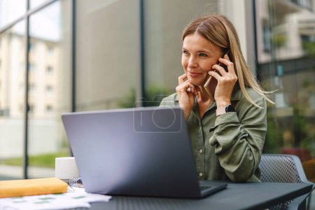 Foto de Businesswoman talking with client and work on laptop outside of office. Distance work concept - Imagen libre de derechos