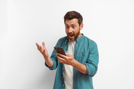 Photo for Man showing surprised gesture while looking on mobile phone on white background. High quality photo - Royalty Free Image