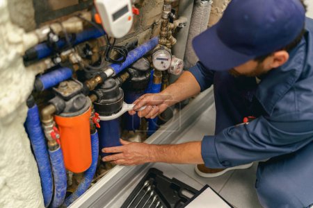 Foto de Handyman en uniforme reparar el sistema de suministro de agua en el hogar utiliza una herramienta especial - Imagen libre de derechos
