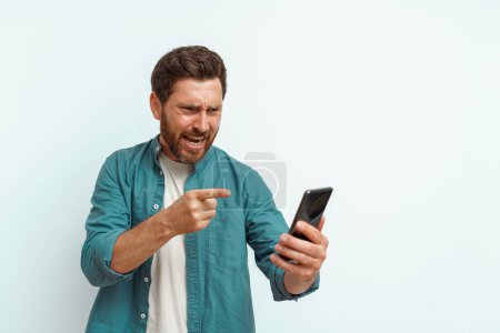 Photo for Man pointing on his mobile phone while standing on white background. High quality photo - Royalty Free Image