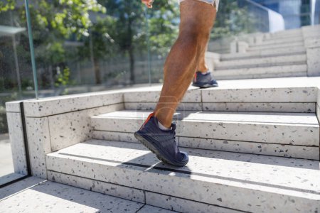Téléchargez les photos : Gros plan des jambes sport coureur homme courant dans les escaliers faire de l'entraînement cardio à la rue extérieure - en image libre de droit