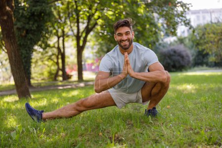 Photo for Smiling man in sportswear is doing warming up before running in the city park. High quality photo - Royalty Free Image