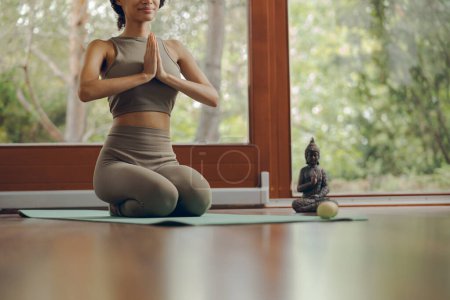 Téléchargez les photos : Gros plan de la jeune femme en vêtements de sport pratiquant le yoga assis sur un tapis à la maison - en image libre de droit