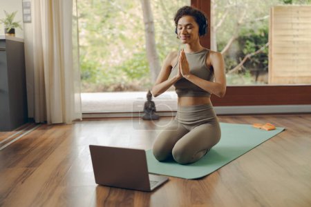 Téléchargez les photos : Femme en casque pratiquant le yoga et écouter la méditation à la maison sur le tapis - en image libre de droit