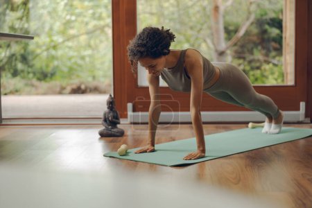 Photo for Young woman standing in plank pose on fitness mat while training at home. High quality photo - Royalty Free Image
