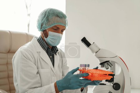 Foto de El hombre científico de uniforme tiene tubos de ensayo en el laboratorio. Medicina e investigación en química - Imagen libre de derechos