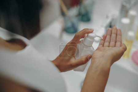 Photo for Close up of woman applying body cream or lotion on hands standing in bathroom - Royalty Free Image