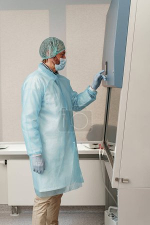 Téléchargez les photos : Homme scientifique en uniforme et masque travaillant dans un laboratoire de recherche médicale. Photo de haute qualité - en image libre de droit