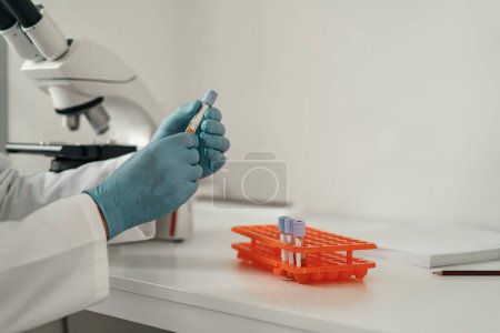 Photo for Close up of scientists hand in gloves putting a small plastic test tube in a microcentrifuge - Royalty Free Image