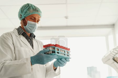 Foto de El hombre científico de uniforme tiene tubos de ensayo en el laboratorio. Medicina e investigación en química - Imagen libre de derechos