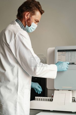 Foto de Hombre científico en uniforme y máscara trabajando en laboratorio de investigación médica. Foto de alta calidad - Imagen libre de derechos