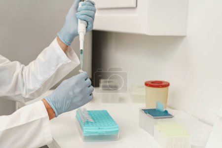 Photo for Male scientist in uniform is using micropipette for biochemical test analysis in medical laboratory - Royalty Free Image
