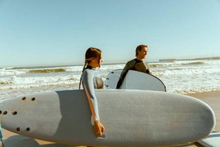Téléchargez les photos : Groupe d'amis avec planches de surf entrant vers l'océan pour surfer sur les vagues. Photo de haute qualité - en image libre de droit