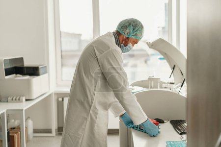 Téléchargez les photos : Un homme scientifique en uniforme tient des éprouvettes en laboratoire. Médecine et recherche en chimie - en image libre de droit