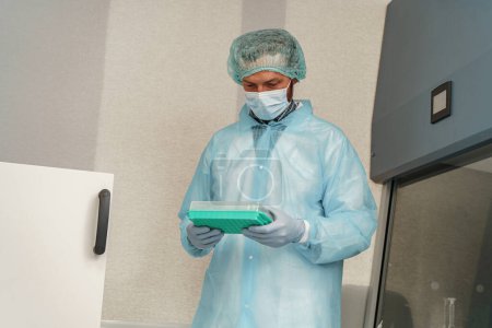 Téléchargez les photos : Scientifique en uniforme et masque tenant des éprouvettes en laboratoire. Médecine et recherche en chimie - en image libre de droit