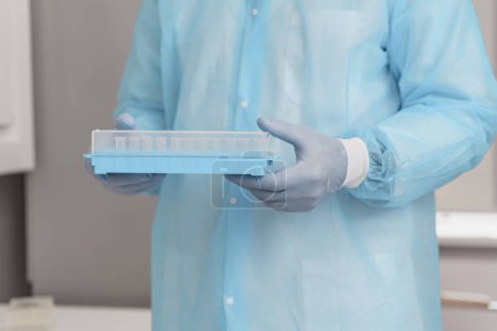 Téléchargez les photos : Un homme en uniforme scientifique tient des éprouvettes en laboratoire. Photo de haute qualité - en image libre de droit