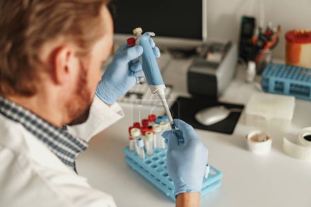 Téléchargez les photos : Homme scientifique en uniforme utilise la micropipette pour l'analyse des tests biochimiques en laboratoire médical - en image libre de droit