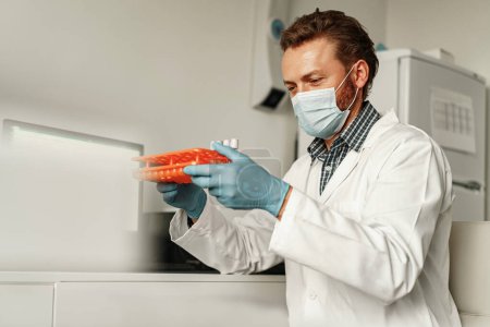 Téléchargez les photos : Un homme scientifique en uniforme tient des éprouvettes en laboratoire. Médecine et recherche en chimie - en image libre de droit