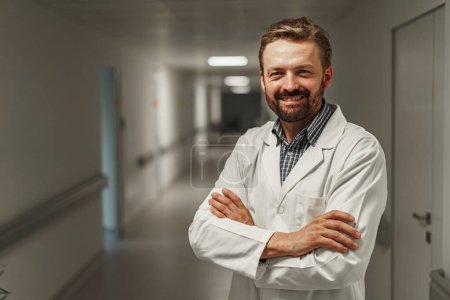 Foto de Médico sonriente parado en el hospital y mirando la cámara con sonrisa - Imagen libre de derechos