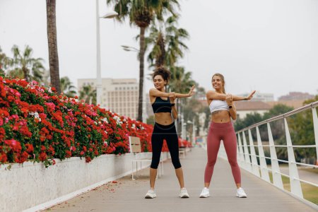 Foto de Las mujeres deportivas hacen ejercicios de calentamiento por la mañana antes de correr el entrenamiento al aire libre. Aptitud saludable - Imagen libre de derechos