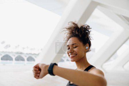 Téléchargez les photos : Jeune femme en tenue de sport en regardant smartwatch et en comptant les calories brûlées. Concept de vie saine - en image libre de droit