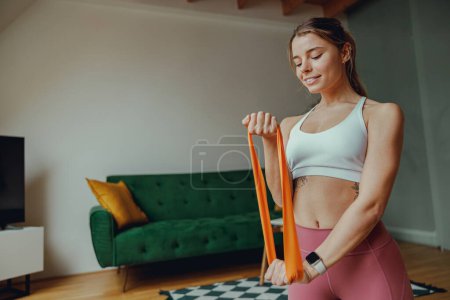 Photo for Close up of woman is kneeling on a yoga mat, holding a resistance band for work out - Royalty Free Image