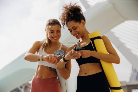 Téléchargez les photos : Jeunes femmes en forme regardant smartwatch et en comptant les calories brûlées. Concept de vie saine - en image libre de droit