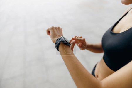 Photo for Close up of woman in sportswear looking on smartwatch after running. Outdoor sports in the morning - Royalty Free Image