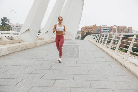 Foto de Mujer atleta activa está trotando en la mañana en el fondo del edificio moderno. Concepto de vida saludable - Imagen libre de derechos