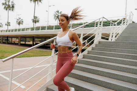 Téléchargez les photos : Jeune femme athlète en vêtements de sport fait du jogging dans la ville tôt le matin. Atteindre le but - en image libre de droit