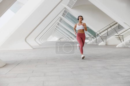 Photo for Active woman athlete is jogging on morning on modern building background. Healthy life concept - Royalty Free Image