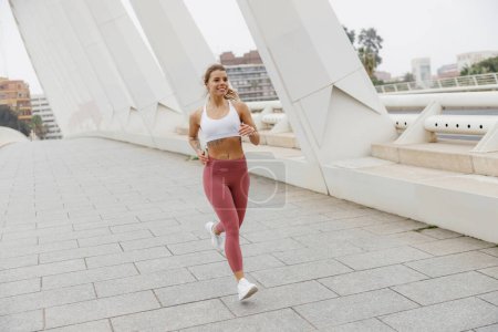 Téléchargez les photos : Athlète femme active fait du jogging le matin sur fond de bâtiment moderne. Concept de vie saine - en image libre de droit