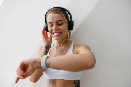 Foto de Joven corredora está teniendo un descanso y escuchando música en los auriculares durante la carrera en la ciudad - Imagen libre de derechos