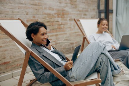 Téléchargez les photos : Femme élégante responsable des ventes parlant par téléphone avec le client assis sur la terrasse de coworking - en image libre de droit