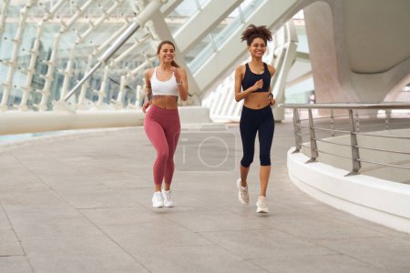 Foto de Dos mujeres están corriendo en la acera, pasando por un edificio - Imagen libre de derechos
