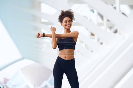 Photo for The woman in the gym is stretching her arms with a smile on her face - Royalty Free Image
