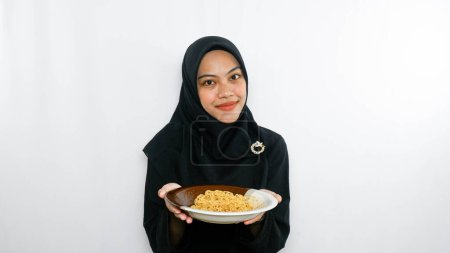 Téléchargez les photos : Jeune femme asiatique isolée sur fond blanc tenant une assiette de nouilles à la fourchette et la mangeant - en image libre de droit