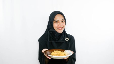 Téléchargez les photos : Jeune femme asiatique isolée sur fond blanc tenant une assiette de nouilles à la fourchette et la mangeant - en image libre de droit
