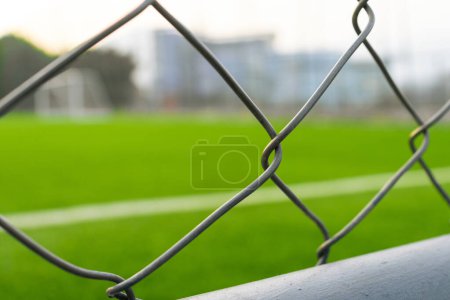 Una vista del campo de fútbol desde fuera de la valla, centrándose en la valla. Después de algunas ediciones.
